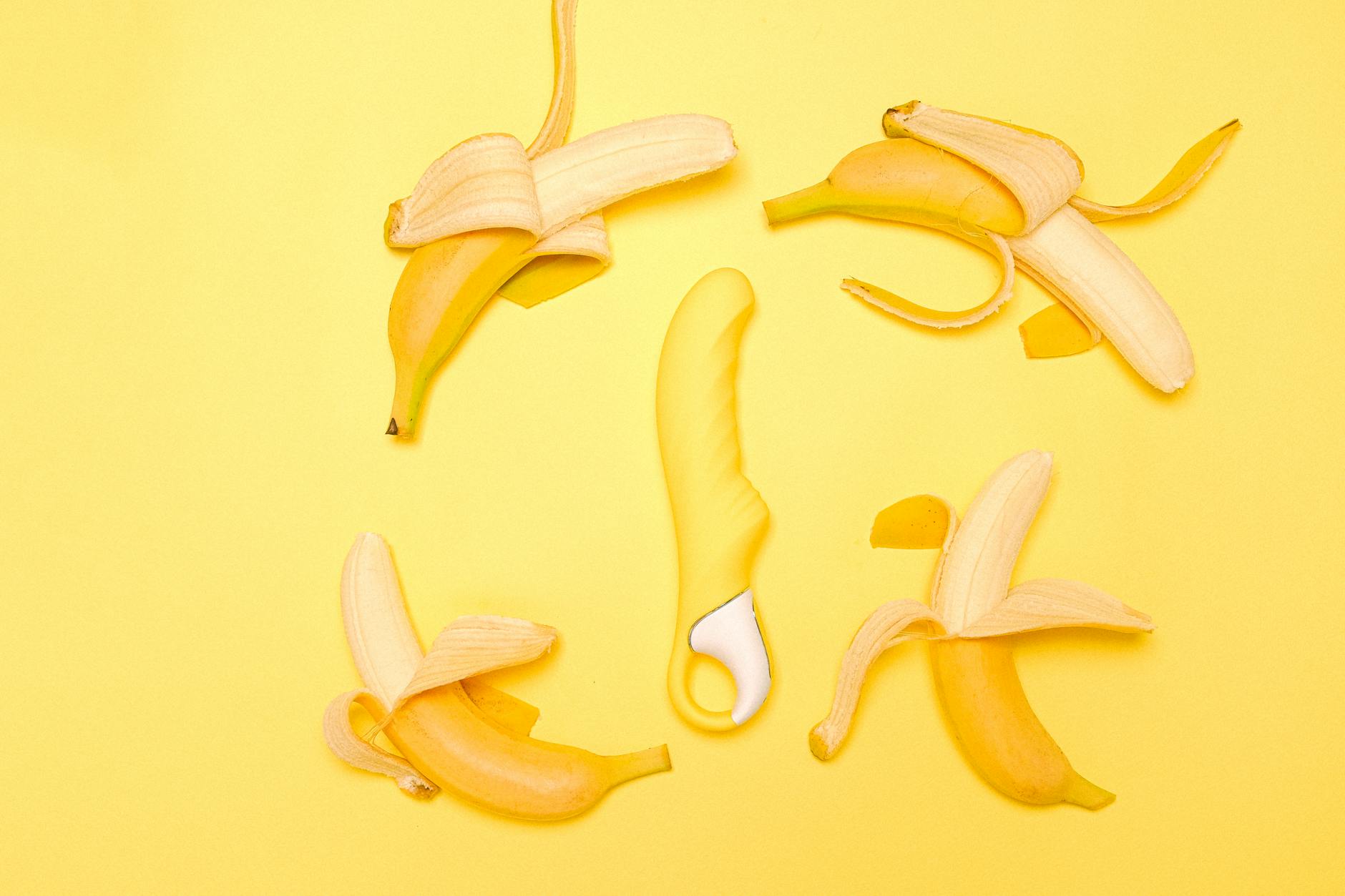 Un vibrateur jaune en silicone entouré de citrons pelés sur un fond jaune vif, symbolisant la fraîcheur et le confort sexuel