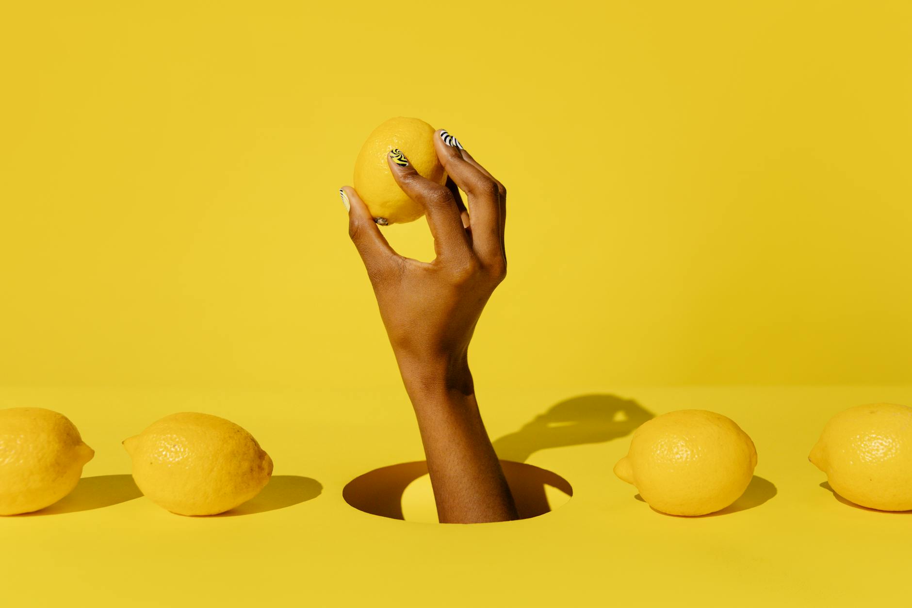 Main tenant un citron frais sur fond rose, symbolisant la stimulation sensorielle et la revitalisation du plaisir