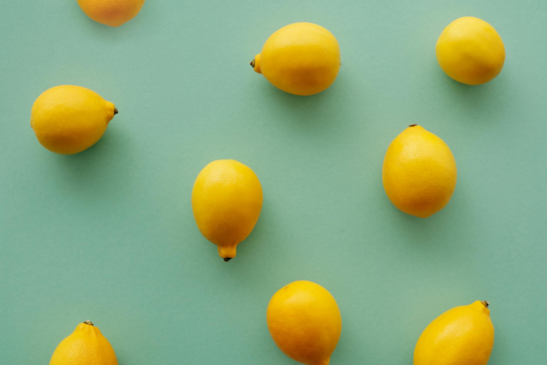 Citrons jaunes lumineux disposés sur un fond vert pastel, créant une composition plates flatlay fraîche et vibrante