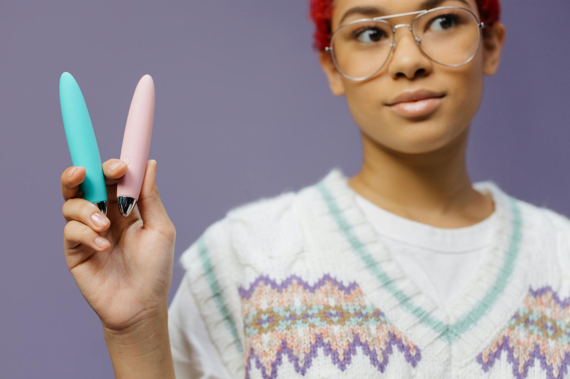 Femme tenant un vibrateur bleu et rose contre un fond violet