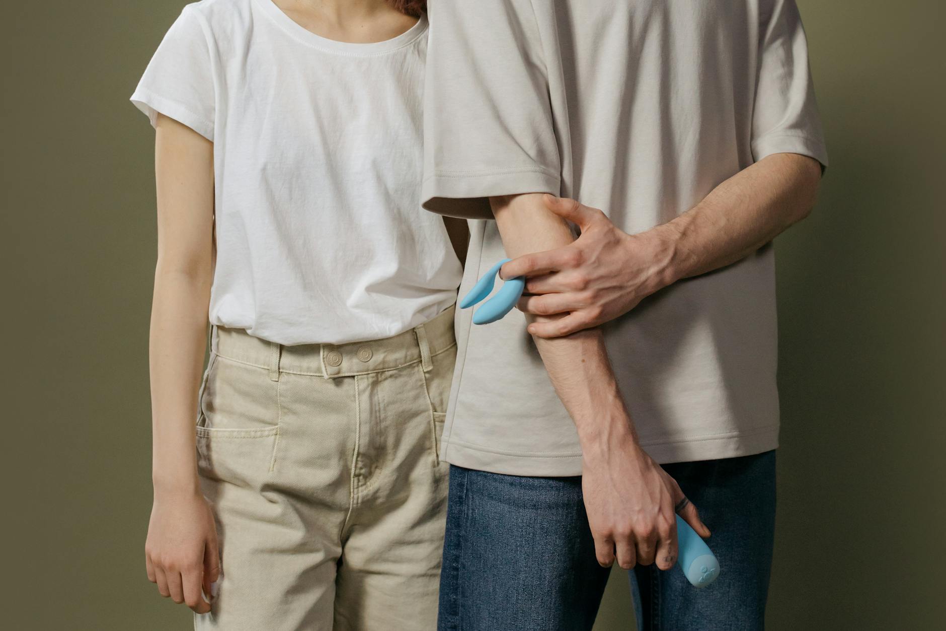 Un jeune couple debout ensemble, tenant un vibrateur bleu, symbolisant l'intimité moderne et la confiance mutuelle.